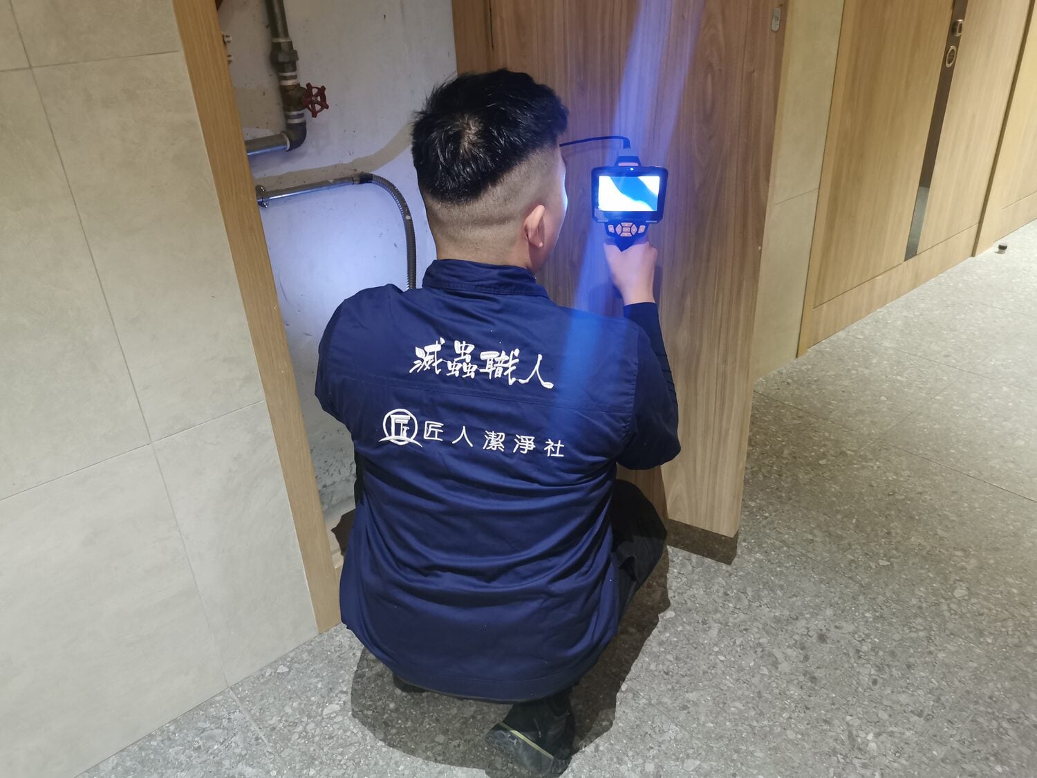 穿著藍色制服的人使用使用內窺鏡進行家居白蟻偵測。