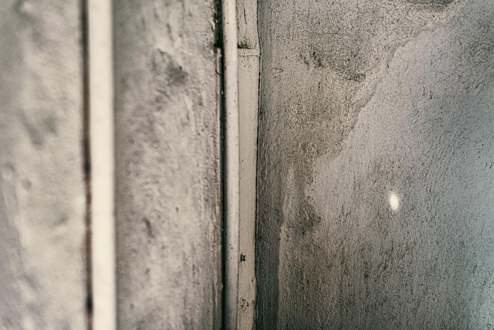 香港濕牆近距離離特寫入，混凝土牆面有水漬與污漬，旁邊有垂直水管，常見回南天潮濕問題.